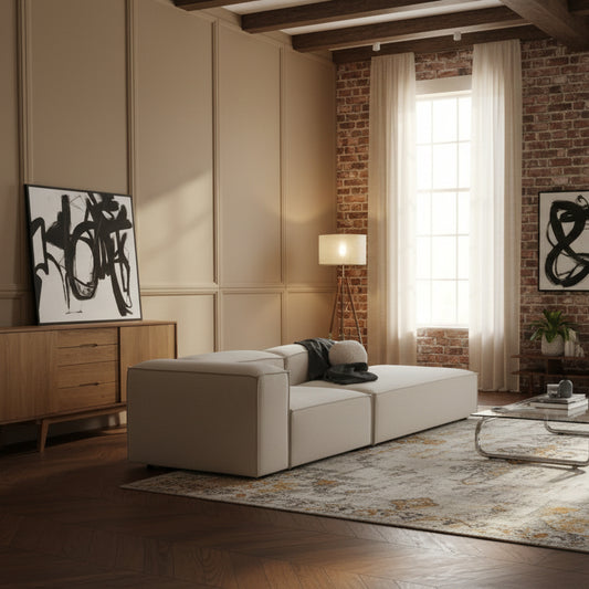 Premium modular Alpha sofa featuring a spacious chaise extension in soft neutral fabric, styled with cushions and modern décor in a refined, light-filled living space