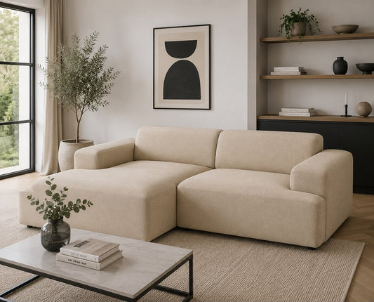 Beige sectional sofa in a modern living room with a coffee table, plant, and wall art.