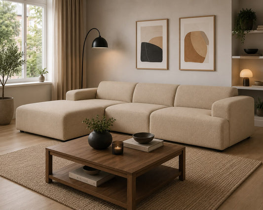 Beige sectional sofa in a living room with a wooden coffee table, lamp, and framed art on the wall.