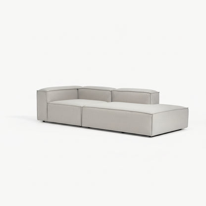 Alpha extended corner sofa configuration with chaise and modular sections in premium neutral fabric, defined by a low-profile and architectural form