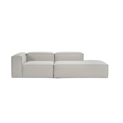 Alpha modular corner sofa with ottoman extension in premium neutral fabric, featuring a refined low-profile silhouette and clean architectural lines