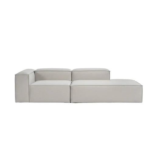 Alpha modular corner sofa with ottoman extension in premium neutral fabric, featuring a refined low-profile silhouette and clean architectural lines