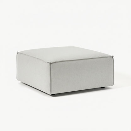 A clean, structured ottoman with a minimalist form, designed to complement modular seating with added versatility and comfort.