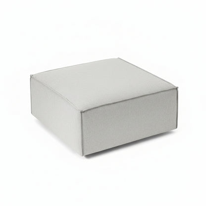 A clean, structured footstool with a low-profile silhouette, designed to complement modular seating while offering versatile comfort and functionality.