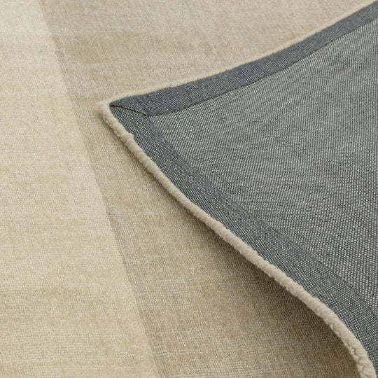 An angled detail view focusing on the hand woven and hand finished construction, revealing natural variation and refined edge detailing on a white background.