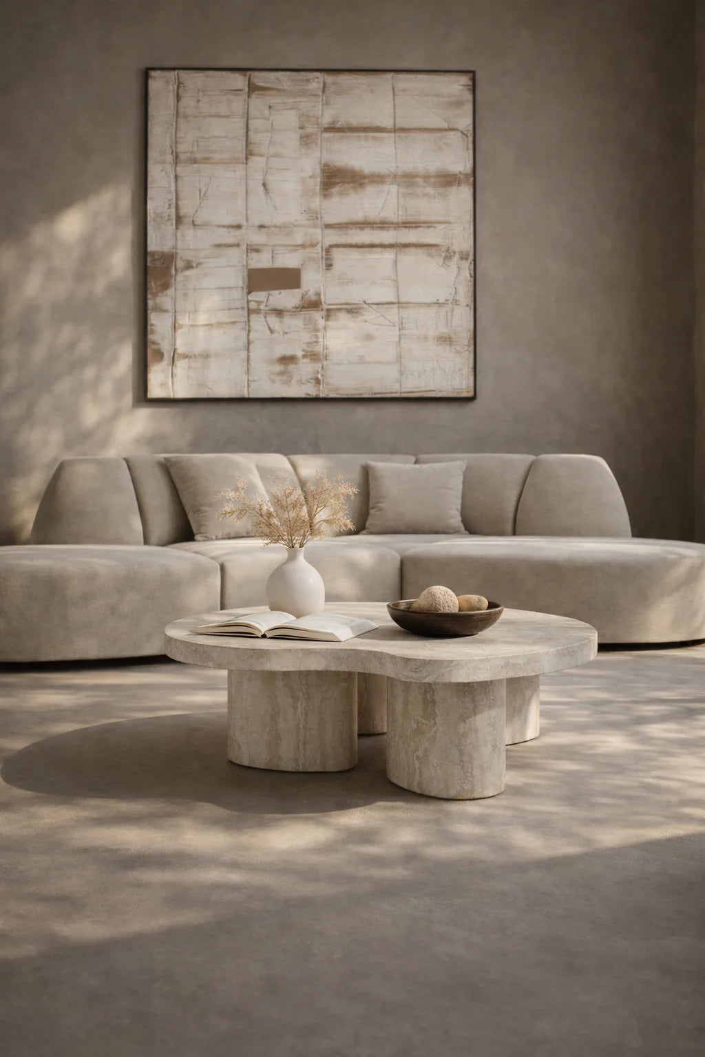Modern living room with a gray sectional sofa, abstract painting, and stone coffee table.